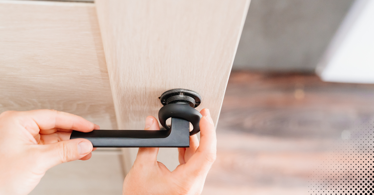 Person installing a modern door handle on a wooden door as part of home maintenance.